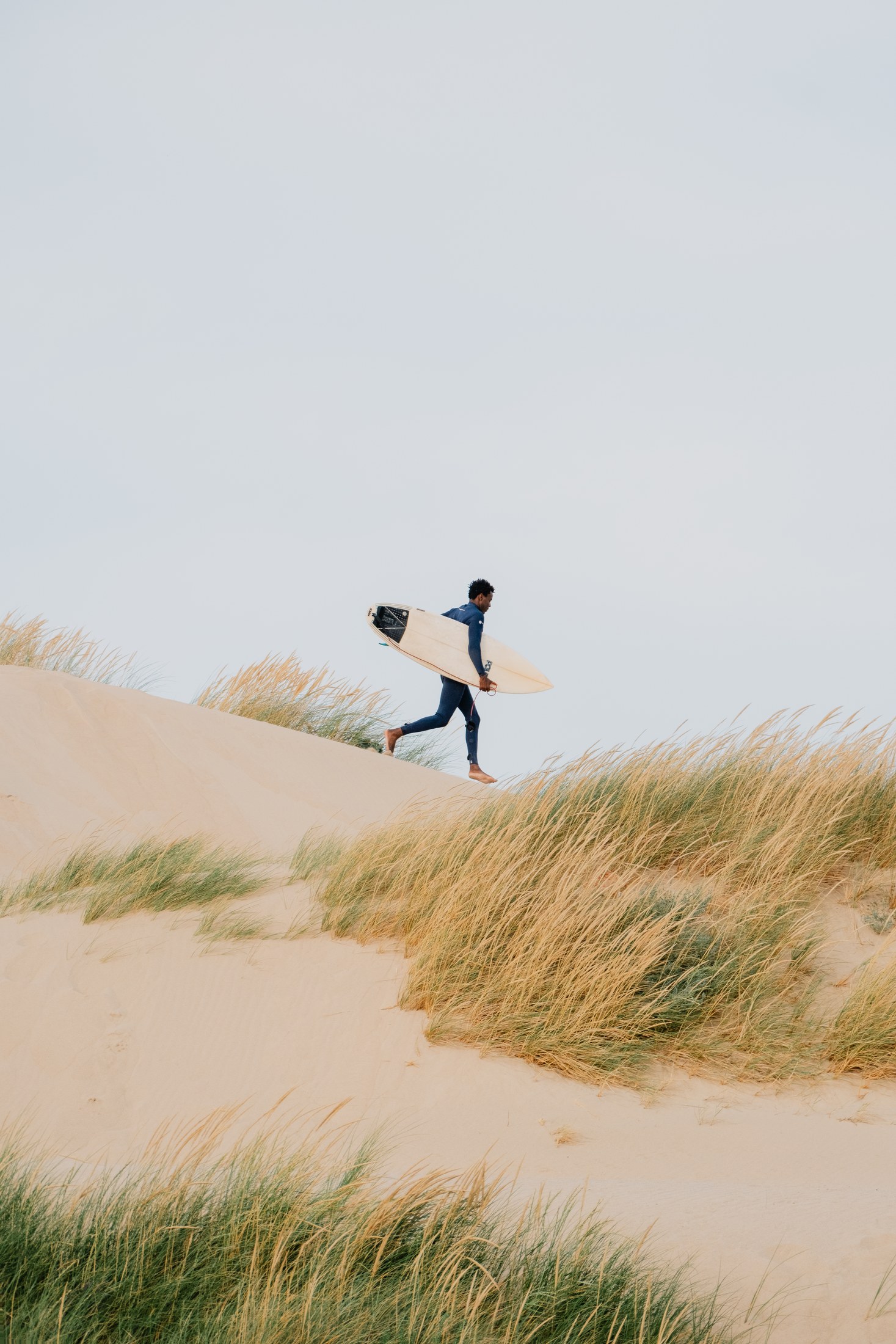 A surfer crossing the dunes in Portugal