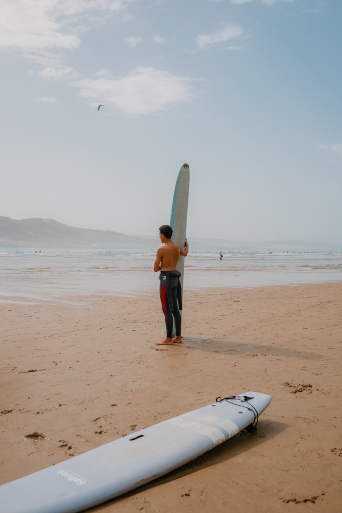 Surfer carrying a board across the beach