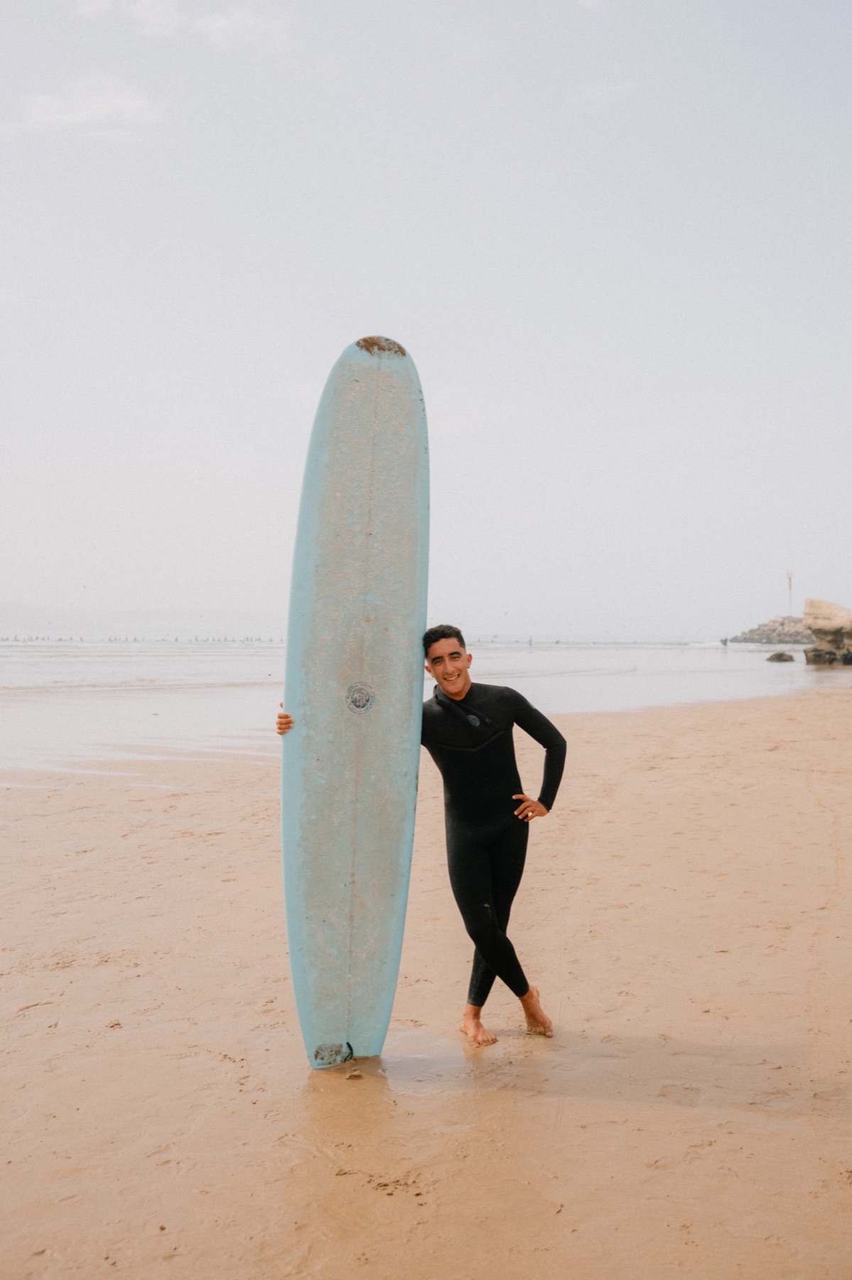 Surfer standing with a board on the beach