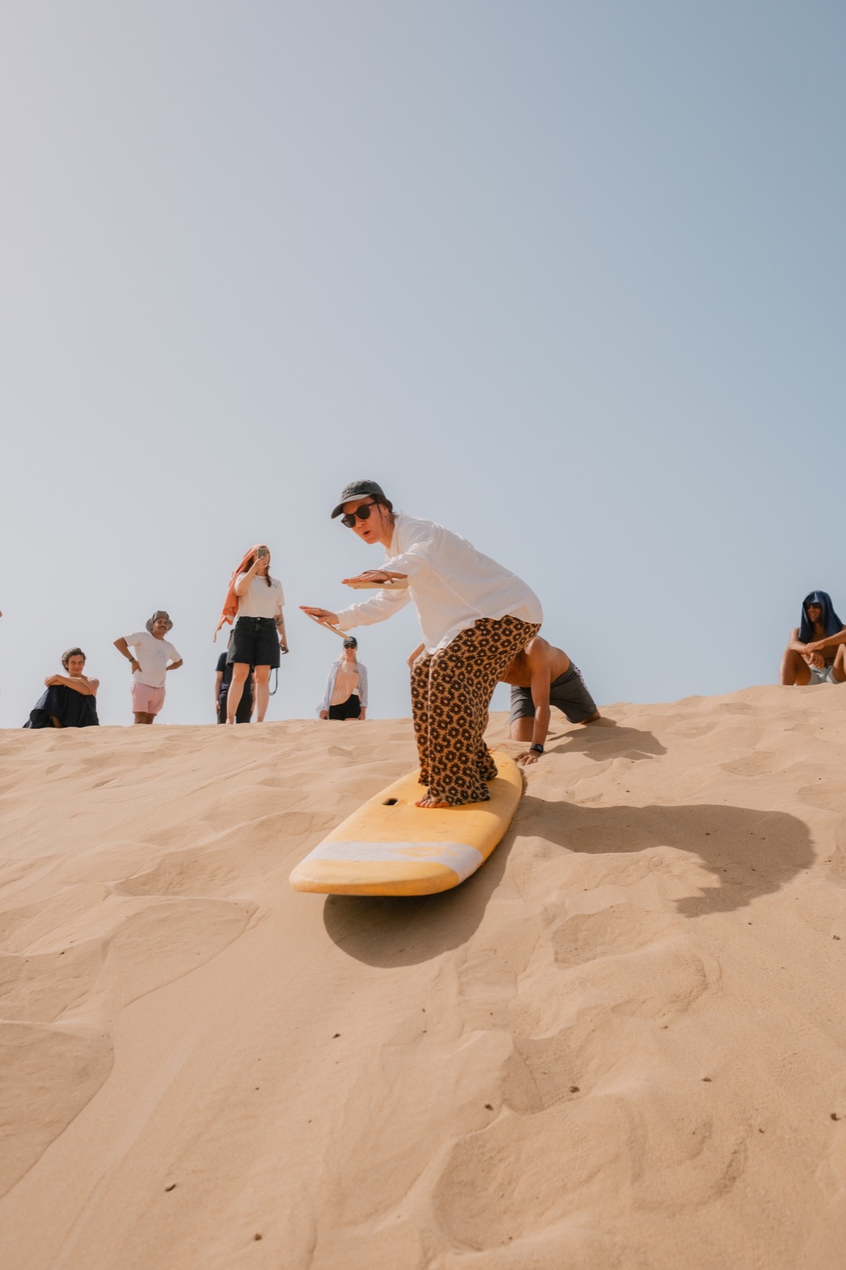 Surfer crossing the dunes with a board