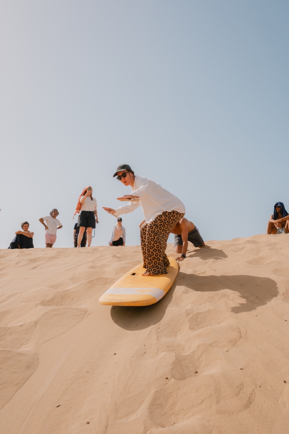 Surfer climbing a dune with a board