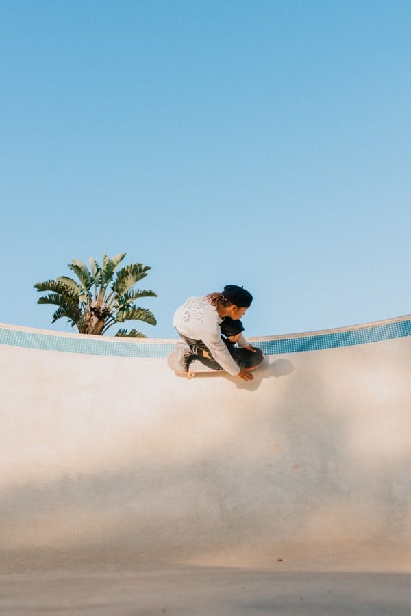 Skater carving through a bowl beneath a wide blue sky