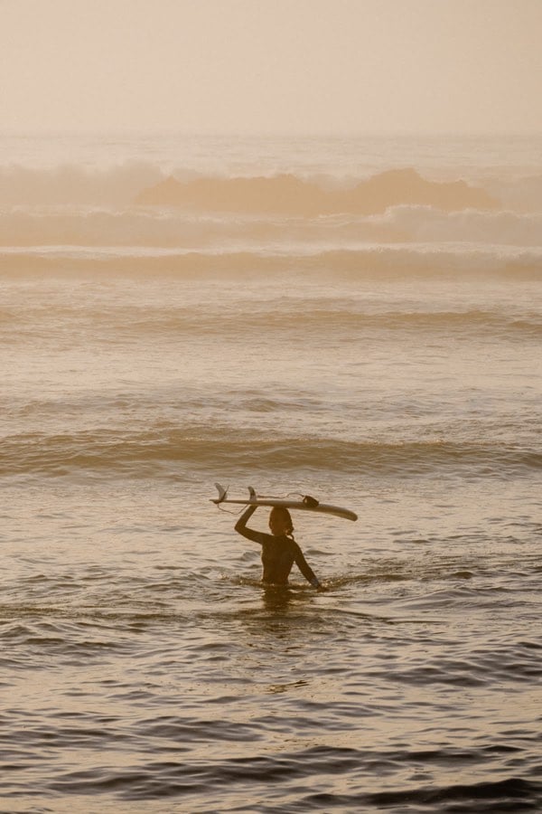 Lone surfer moving through warm coastal haze