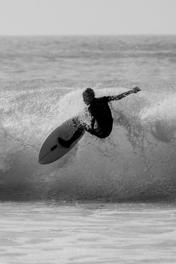 Black and white photograph of a surfer inside a wave