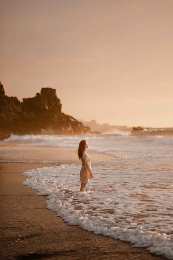 Woman standing in the sea at golden hour