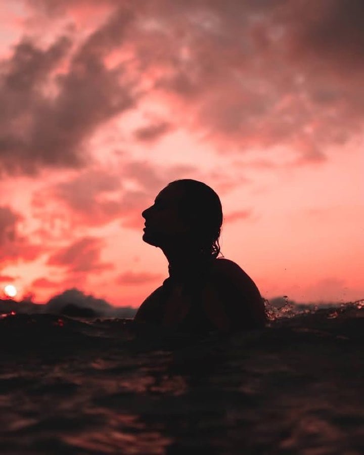 Silhouette in the sea beneath a pink sunset