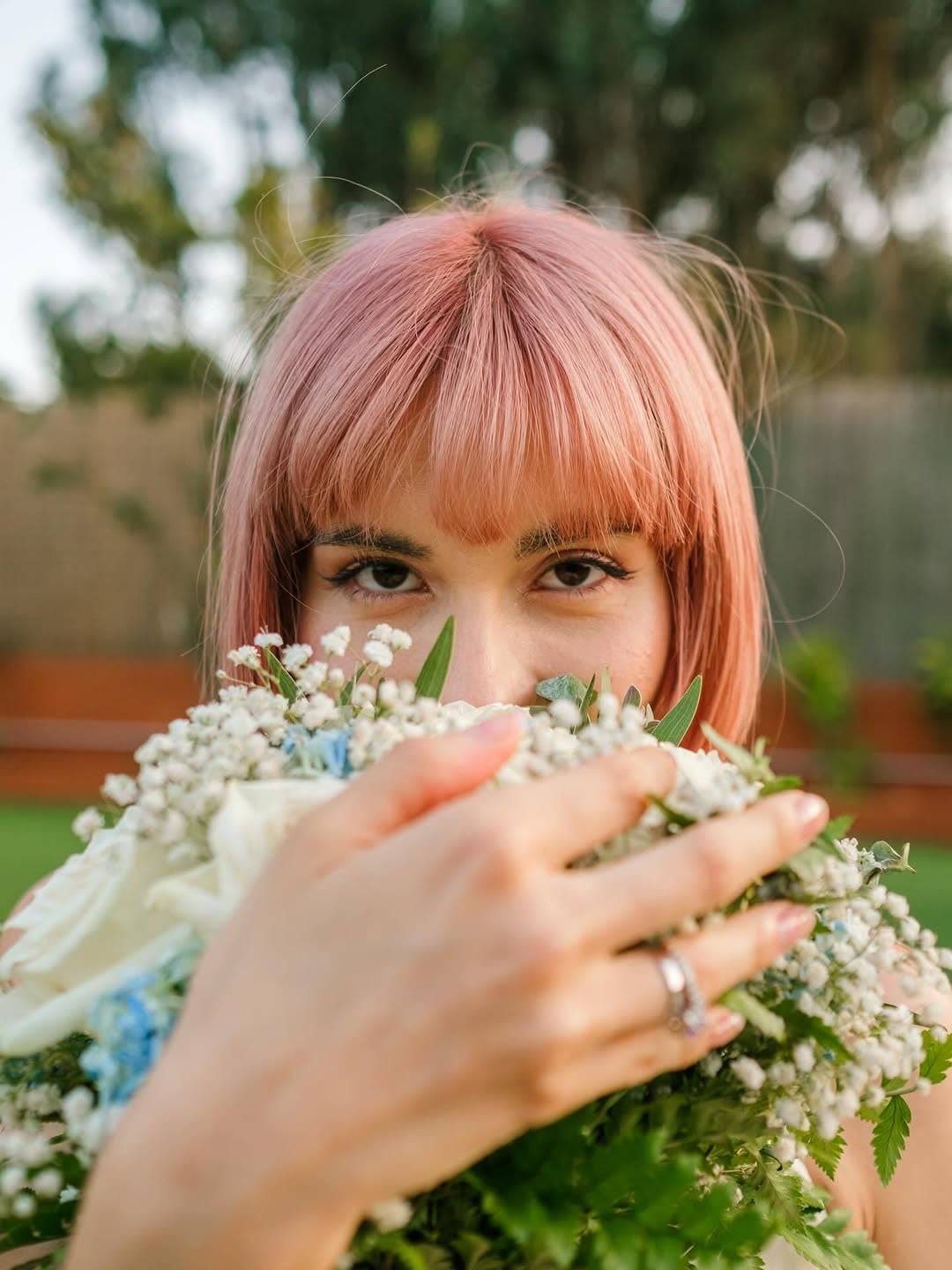 Pink-haired bride looking over her bouquet
