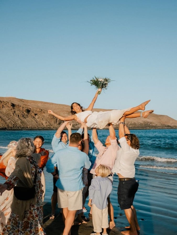 Wedding party lifting the bride beside the sea