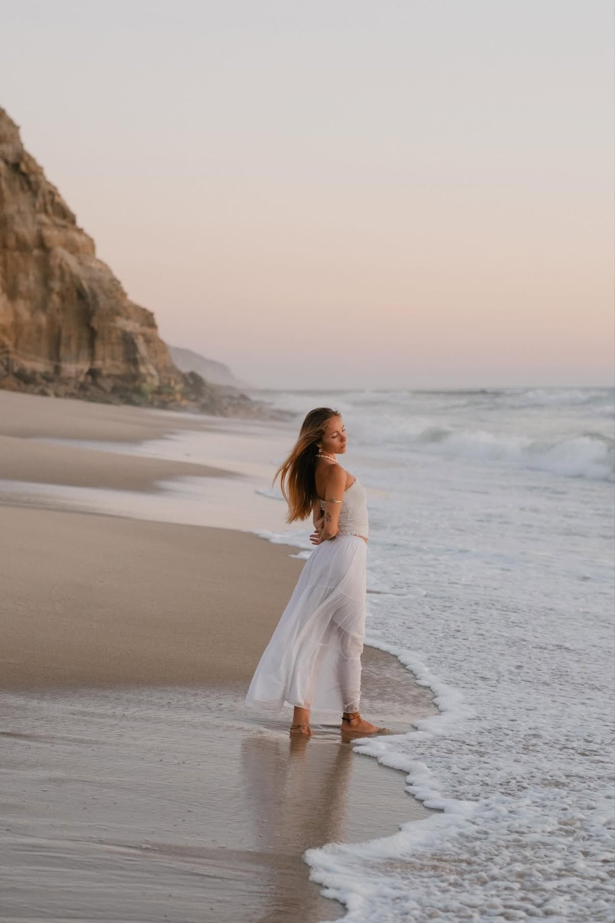 Woman in white walking at the shoreline by Suso Garcia